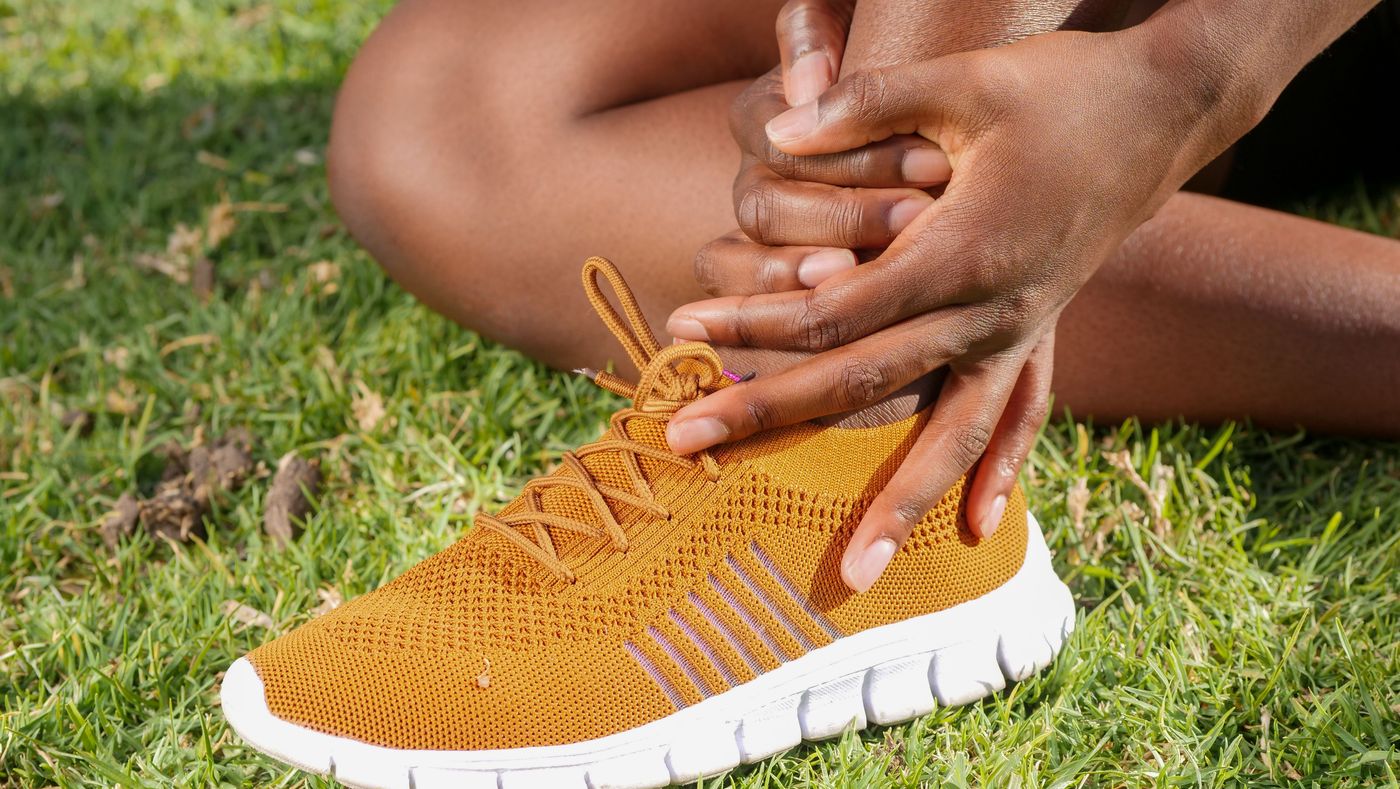 Hands holding an ankle above a running shoe