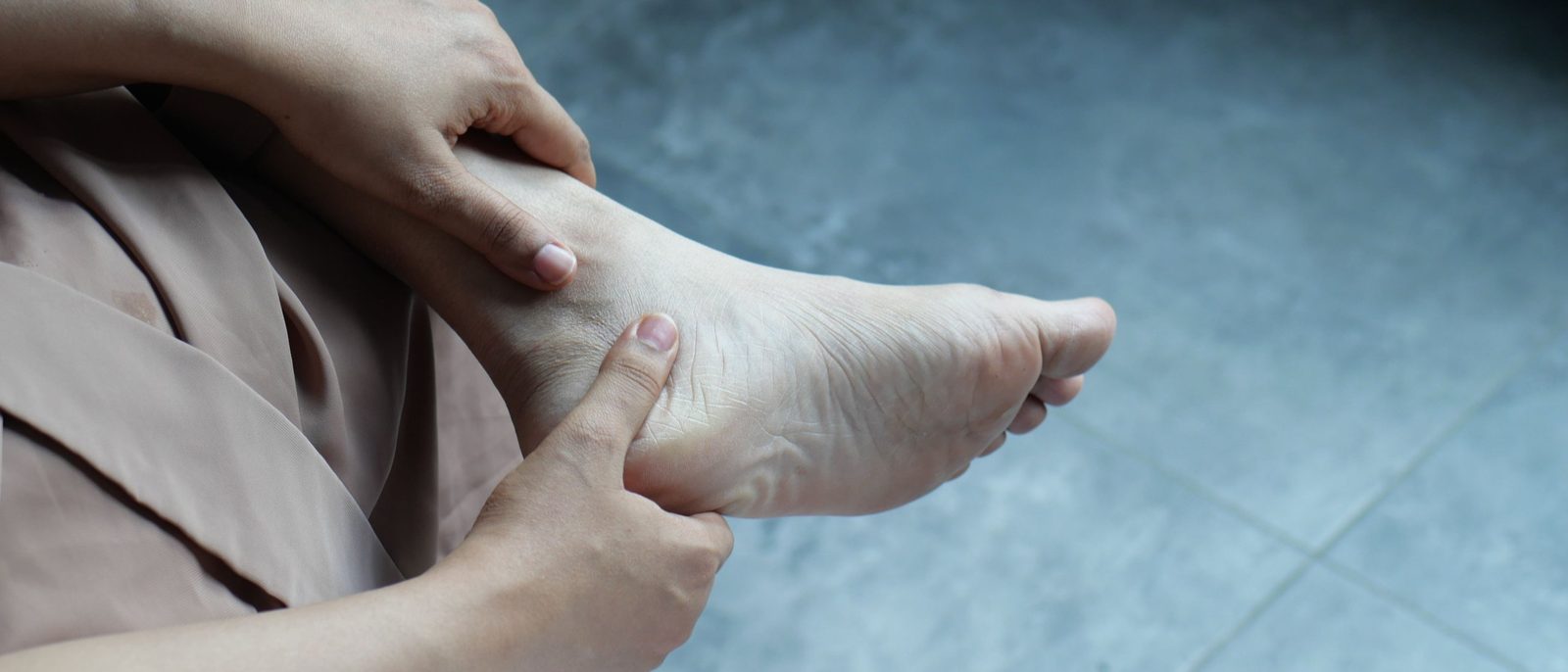 Thumb pressing into the underside of a bare heel