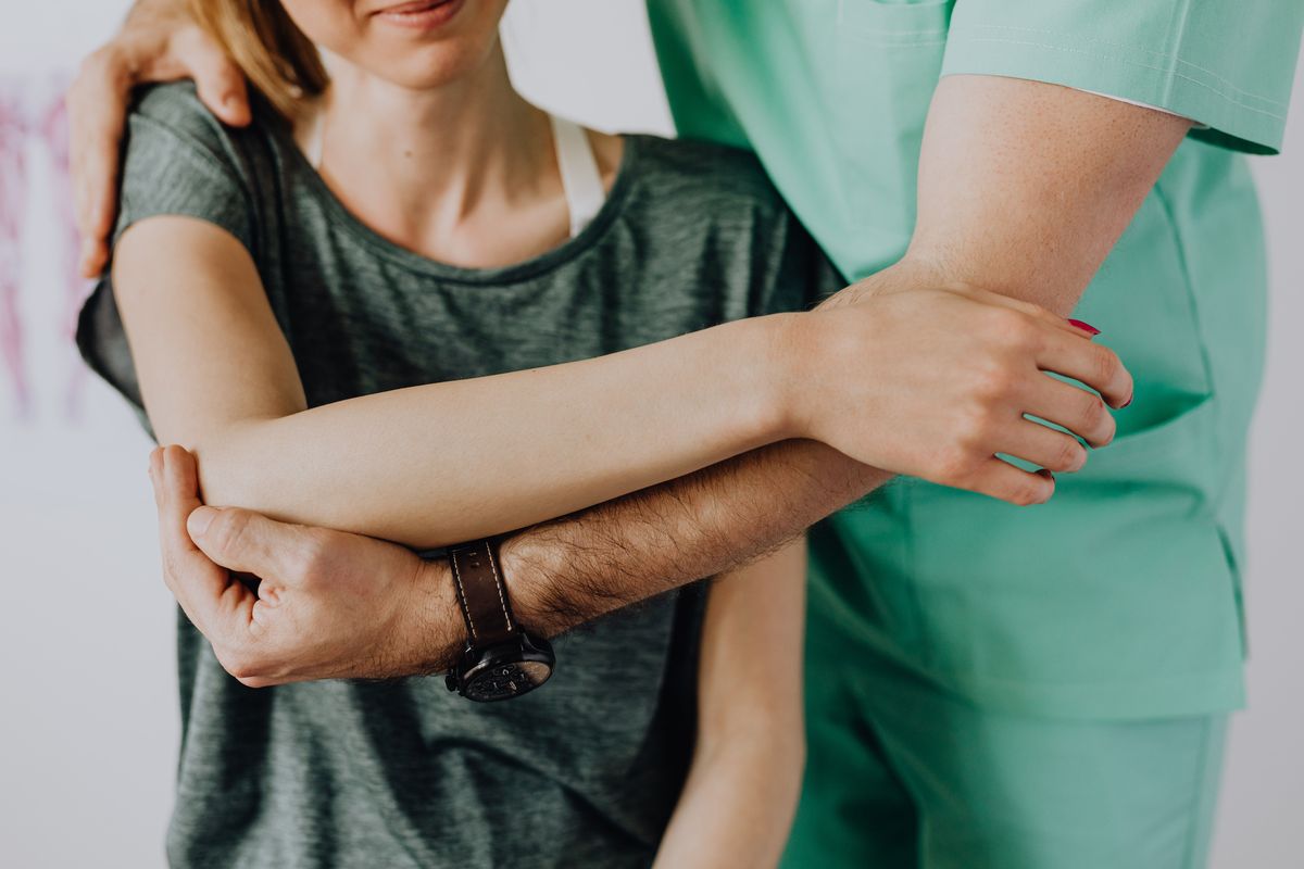 A physiotherapist positioning a client’s arm and shoulder